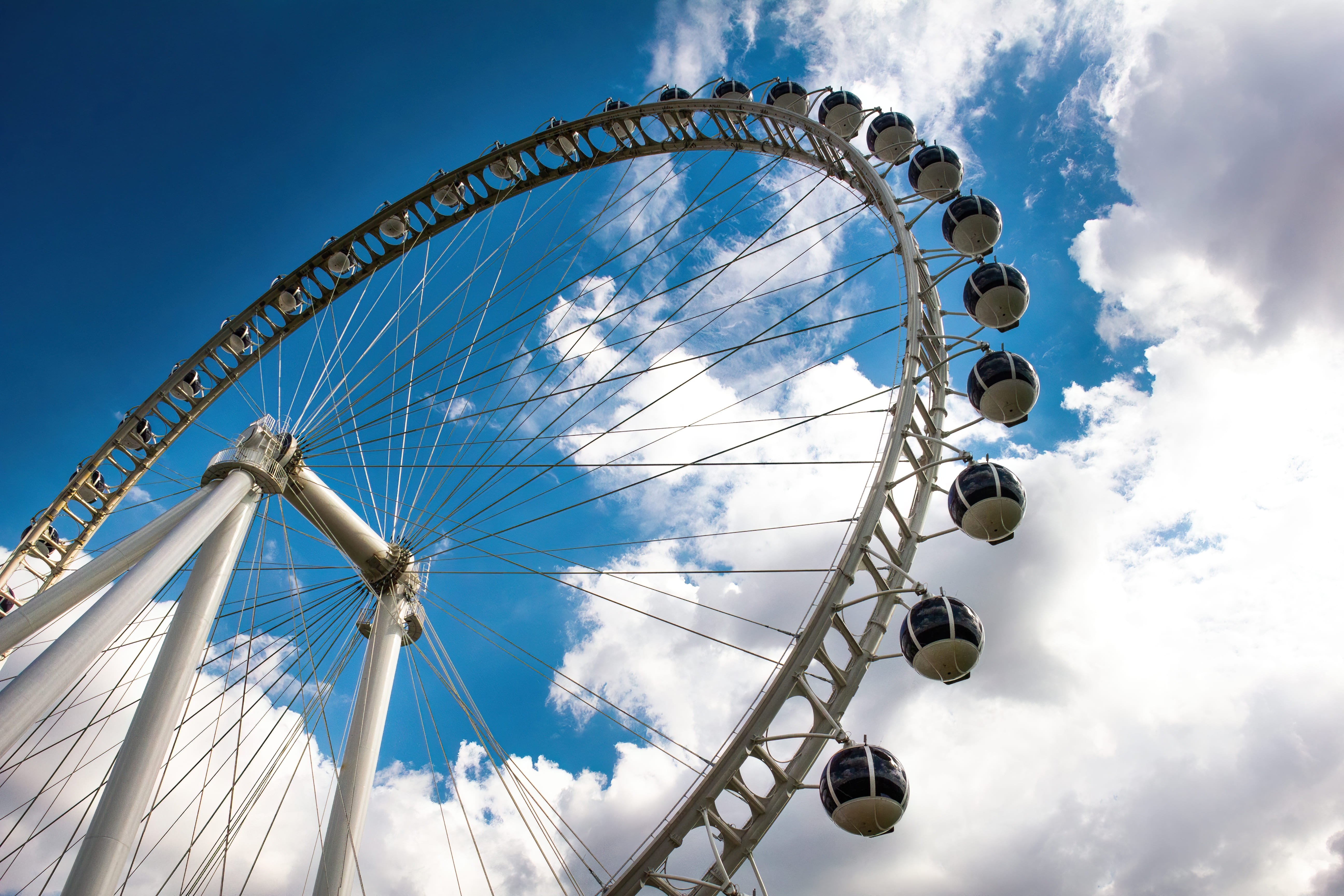 Roda-gigante do Parque Villa-Lobos, em São Paulo, vista de baixo, com estrutura metálica em destaque contra o céu azul com nuvens.