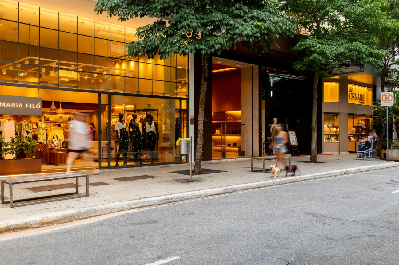 Vista da Rua Oscar Freire, no Jardim América, em São Paulo, com lojas de moda, vitrines iluminadas e movimento urbano em uma das ruas mais famosas da cidade.