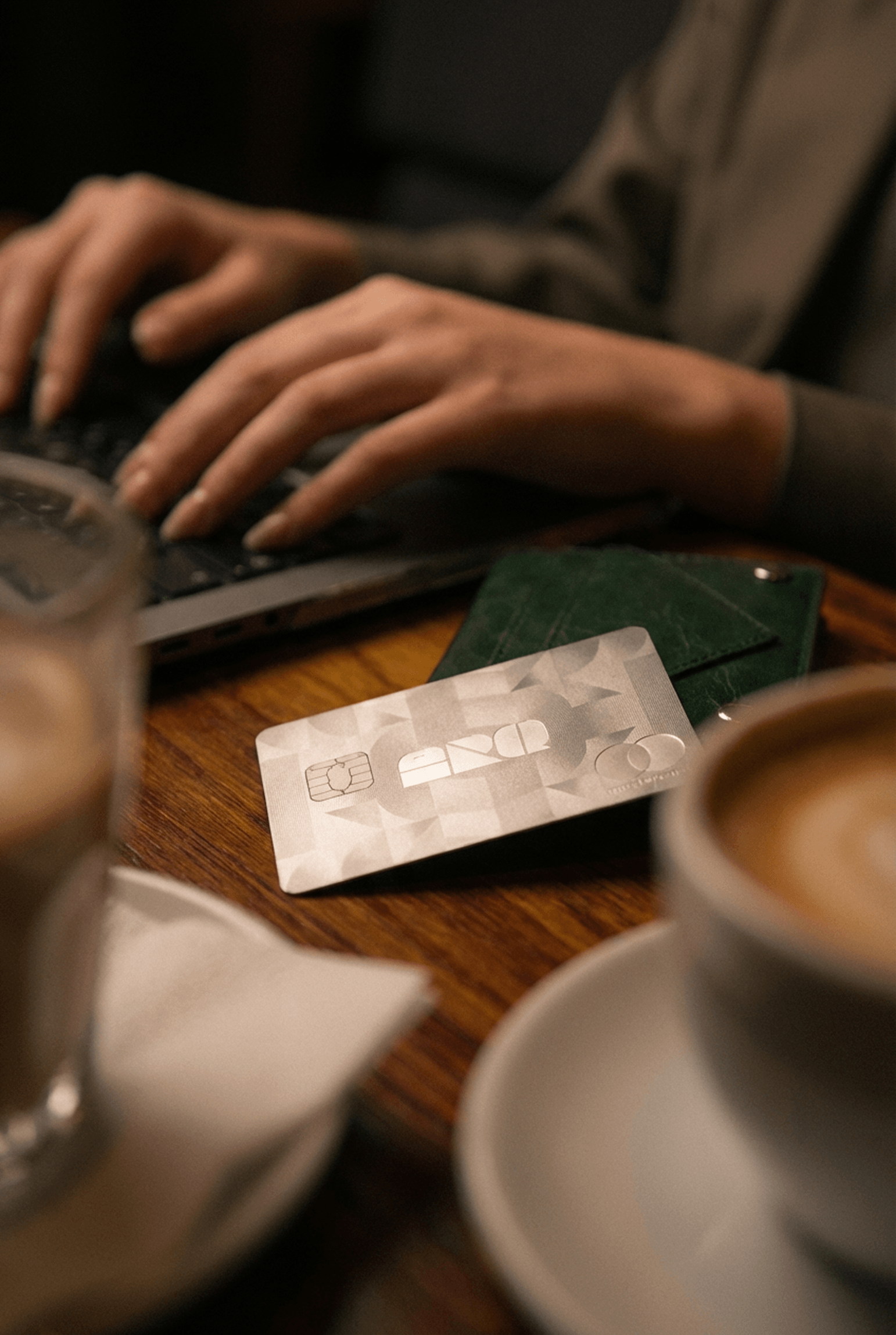 Pessoa usando notebook ao lado de um cartão e uma xícara de café, representando planejamento financeiro digital, pagamentos internacionais e organização de gastos para viajar com mais controle.