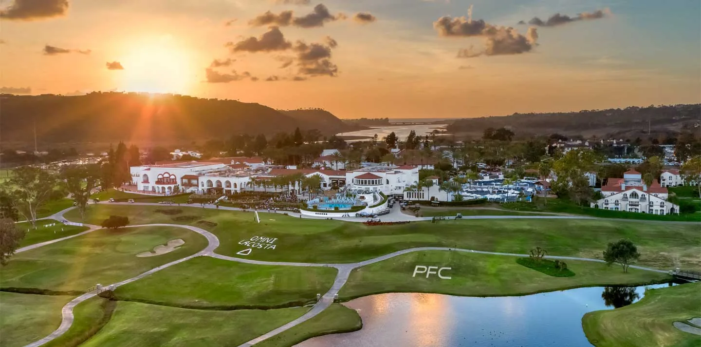 Aerial view of a resort and golf course at sunset, with a lake in the foreground.