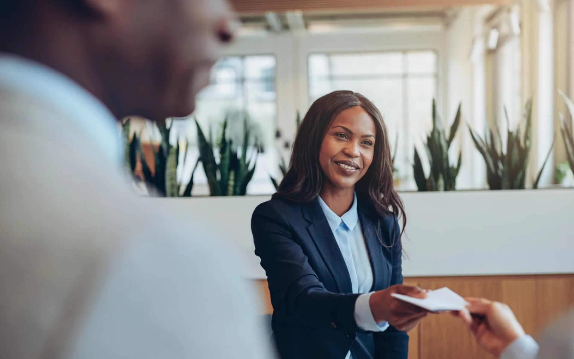 A hotel receptionist hands a keycard to a guest across the front desk.