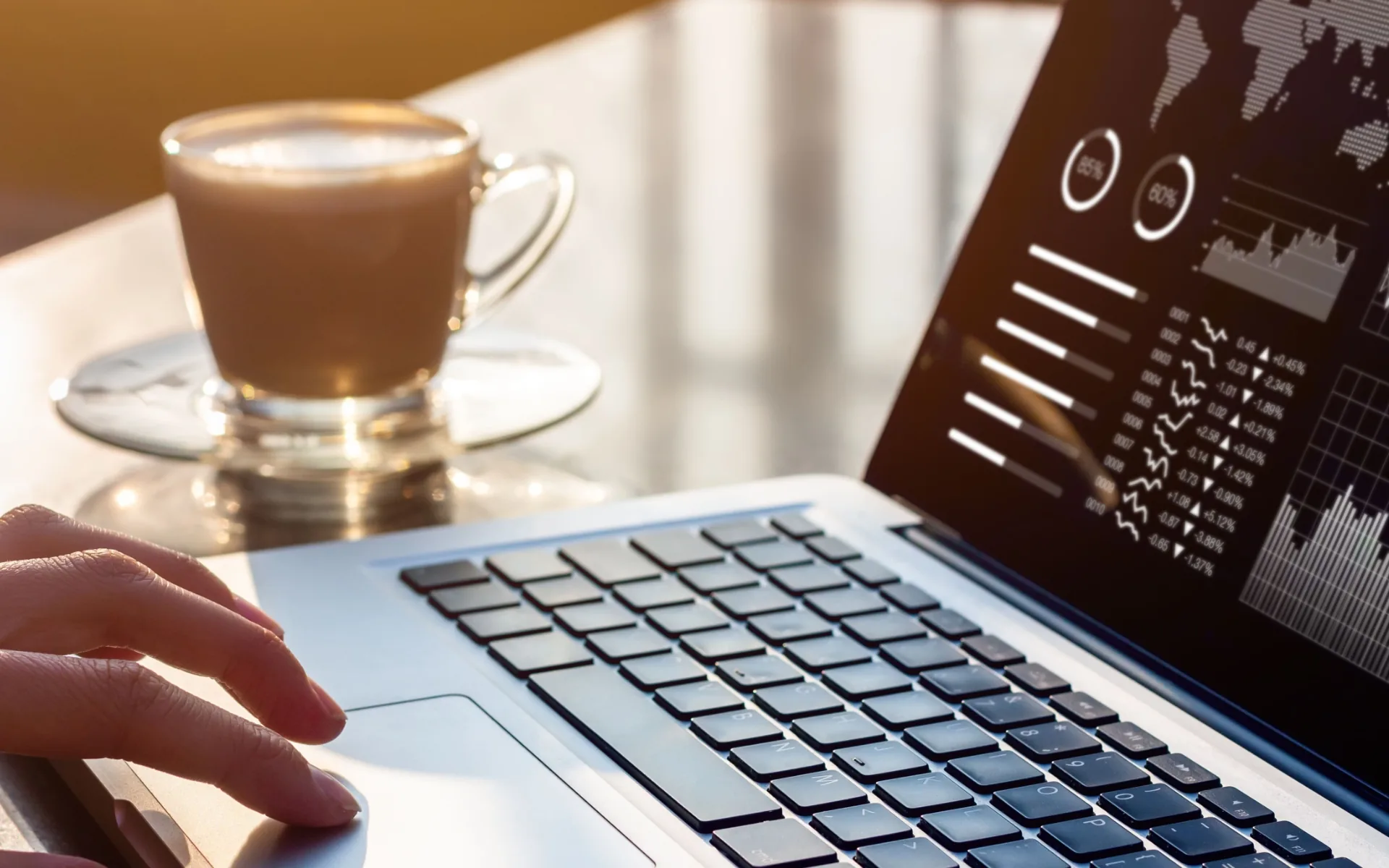 A laptop showing an analytics dashboard on a desk beside a cup of coffee.