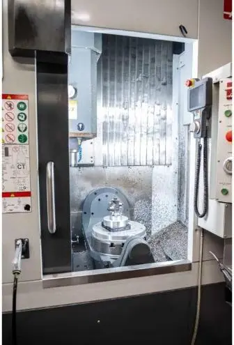 A machined metal part fixtured inside a CNC machining center.