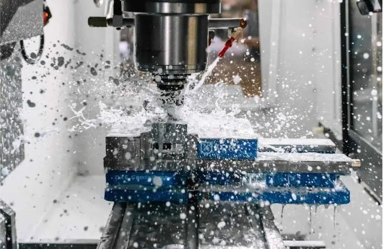 Coolant spraying over a rotating cutter during CNC milling.