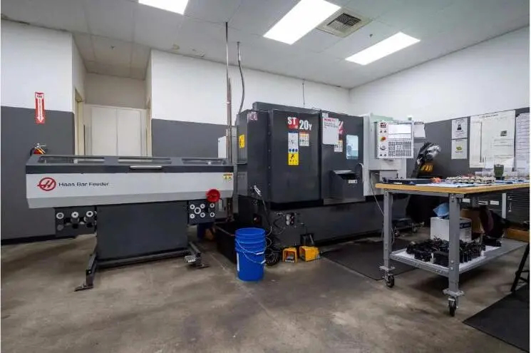 A CNC lathe with bar feeder on a precision machine shop floor.