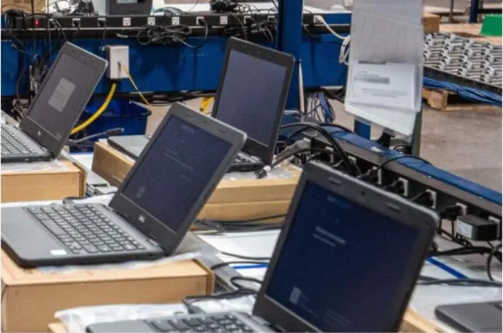 Several laptops open on a configuration line displaying setup screens.