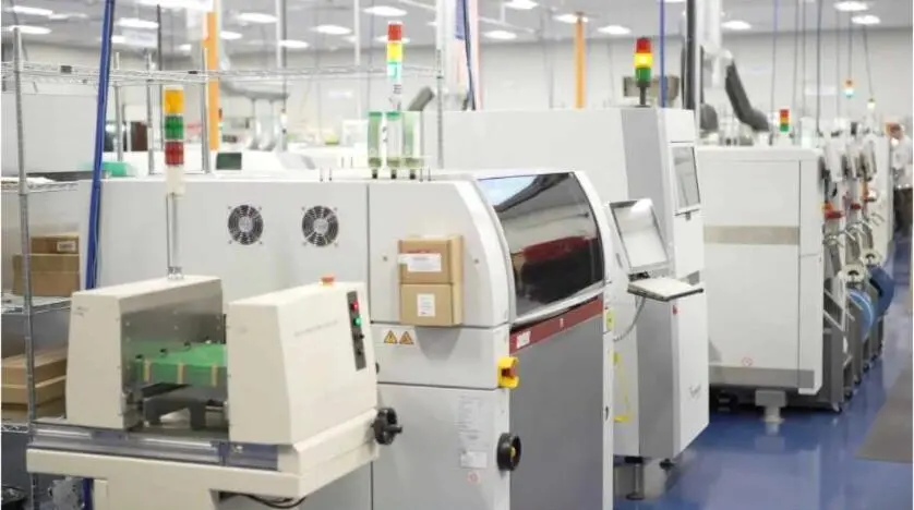 A row of automated surface-mount assembly machines in a clean electronics facility.