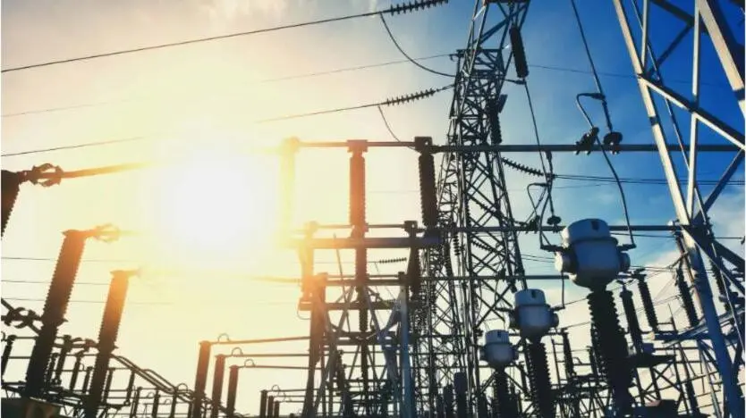 A high-voltage electrical substation with transmission towers against the sky.