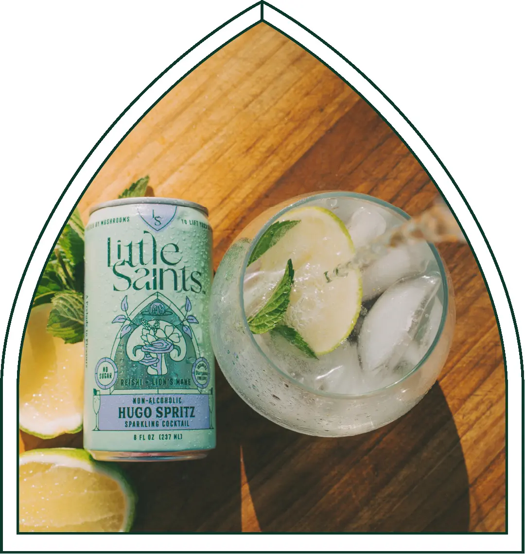 Overhead view of a Little Saints Hugo Spritz can and cocktail with lemon on a wooden board.