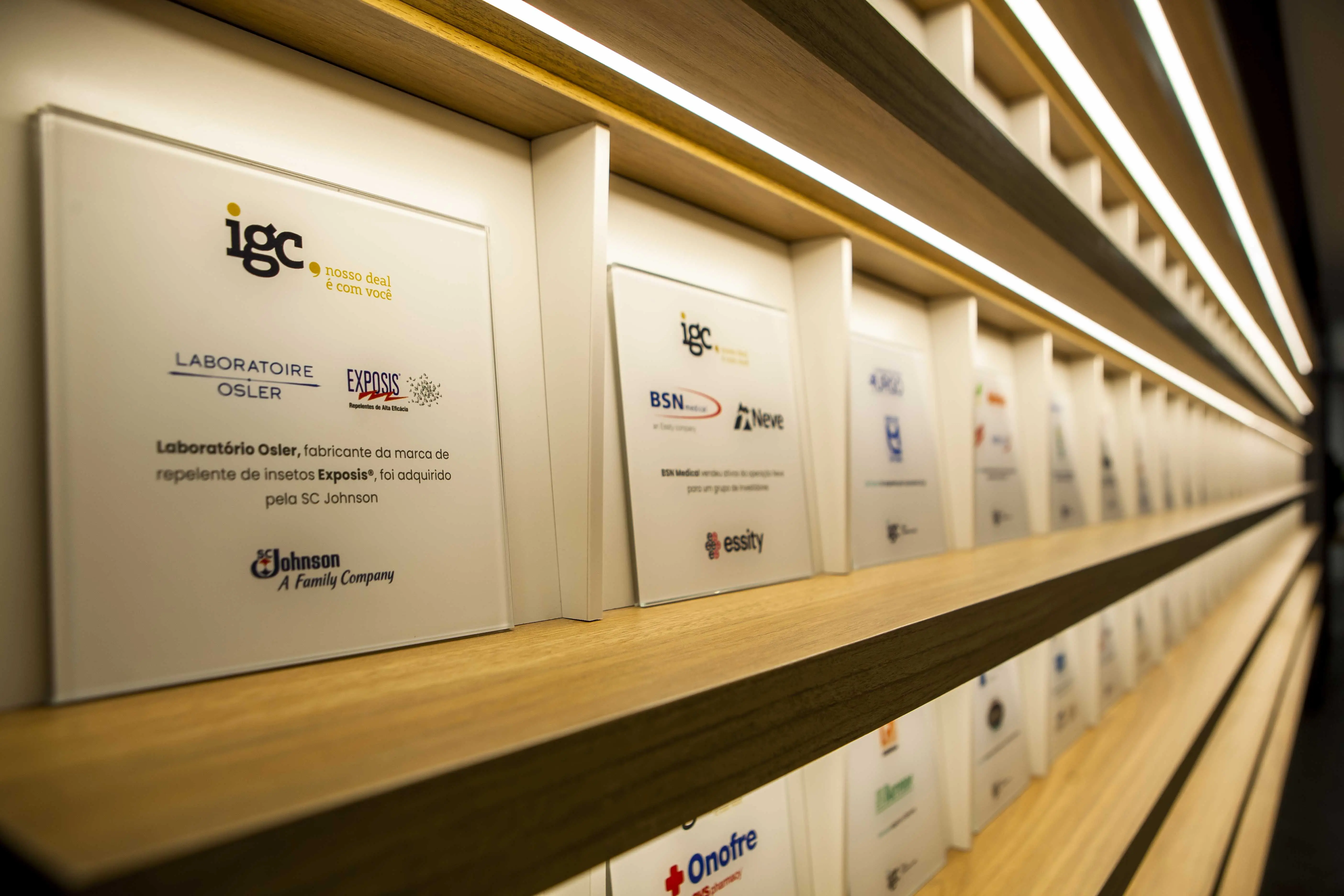 Corredor da igc partners revestido pelas placas comemorativas das transações de M&A assessoradas pela casa
