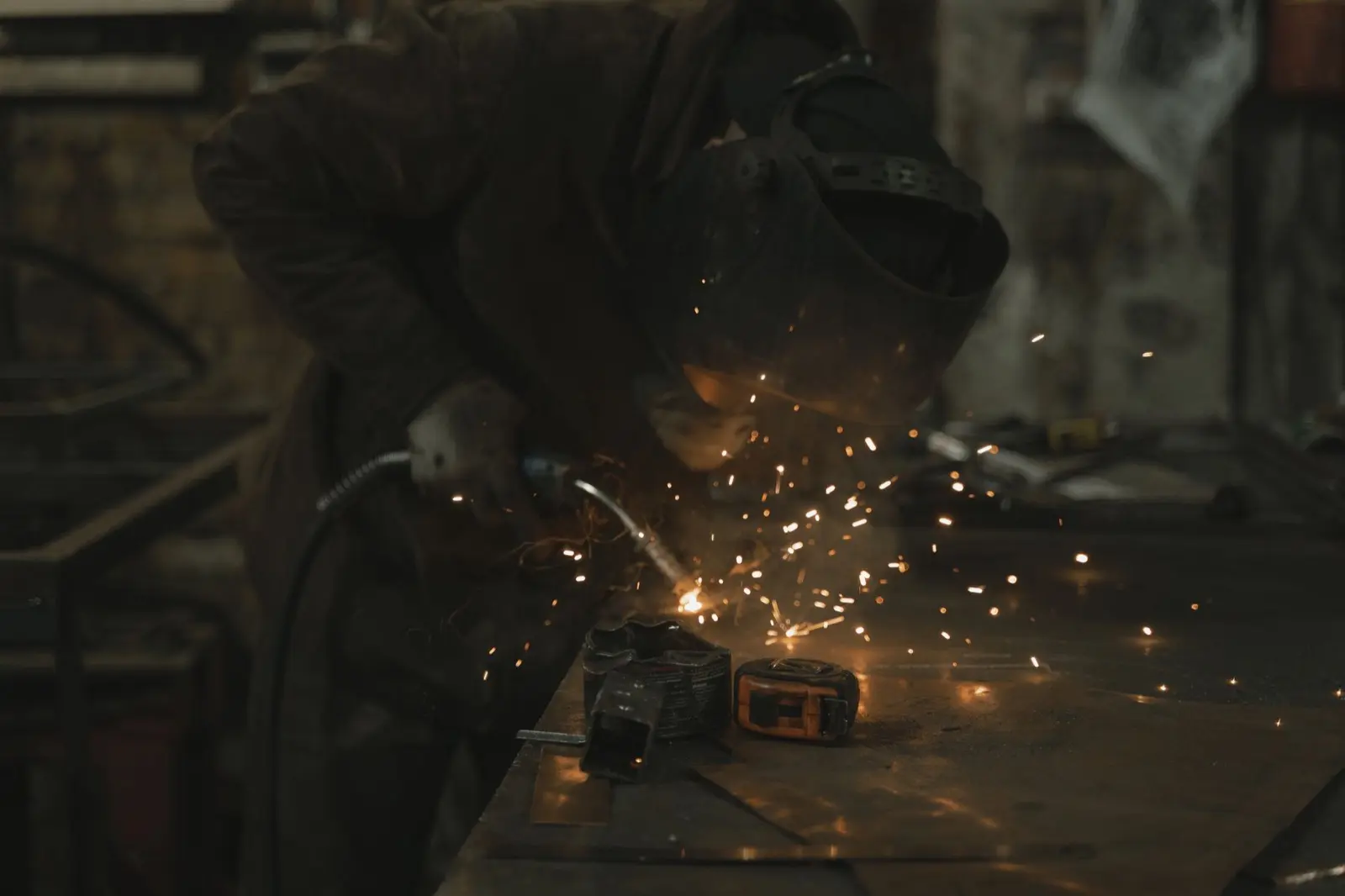Welder producing bright sparks while welding a metal component