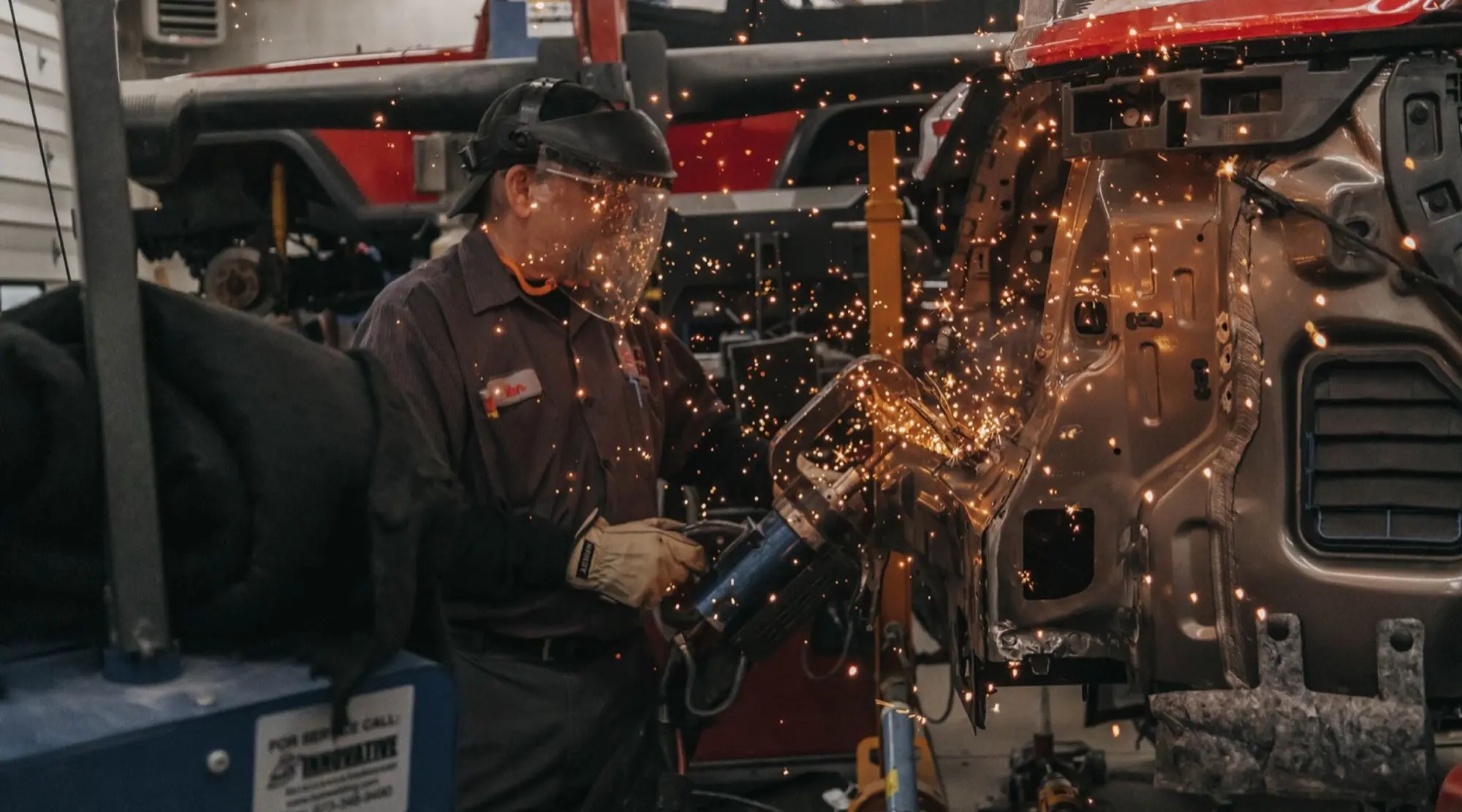 Worker fabricating an automotive engine component with sparks